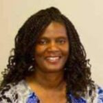 Smiling woman with braided hair, colorful blouse.