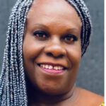 Smiling woman with braided gray hair.